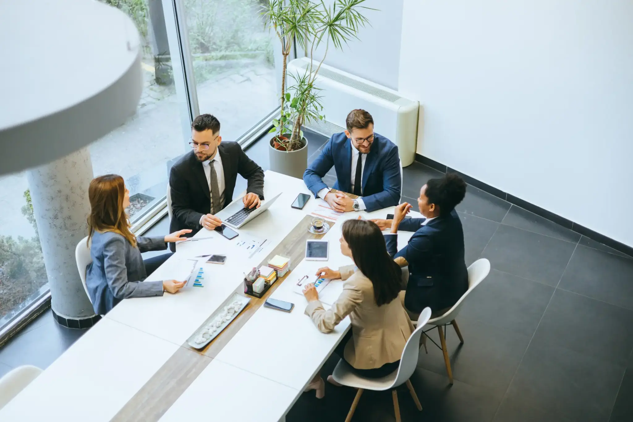 Sechs Personen in Businesskleidung bei einer Besprechung in einem modernen Konferenzraum