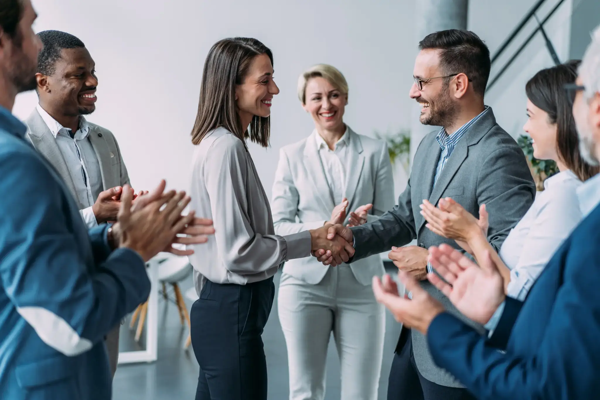 Geschäftsleute gratulieren einer Kollegin bei der Arbeit – symbolisch für betriebliche Arbeitskraftabsicherung im Team