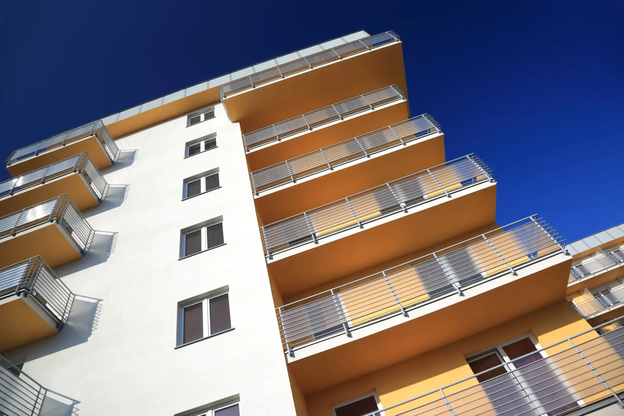 Modernes Mehrfamilienhaus mit Balkonen und blauem Himmel