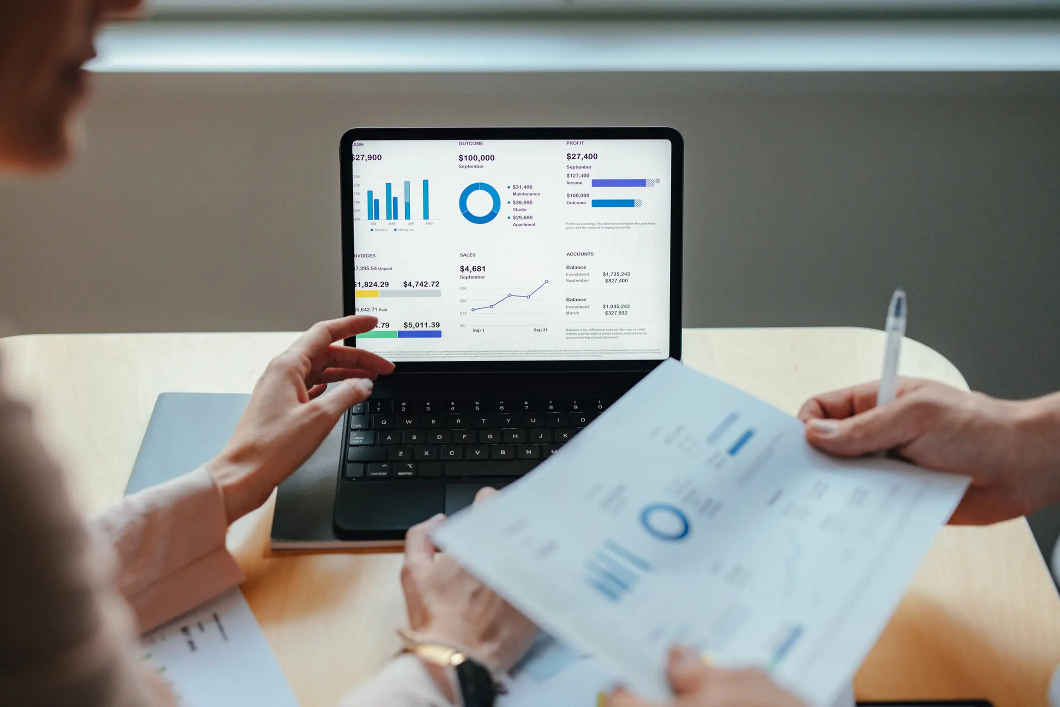 Zwei Personen besprechen am Laptop mit Finanzgrafiken und Diagrammen den Businessplan für einen Onlineshop