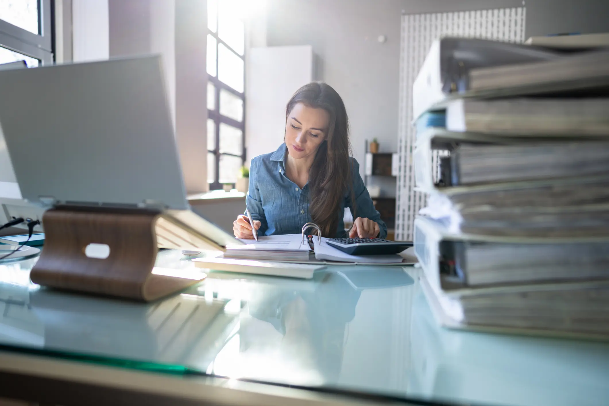 Junge Frau arbeitet konzentriert im Büro mit Akten und Laptop – Symbolbild für Dienstunfähigkeit und Absicherung im Beamtenberuf