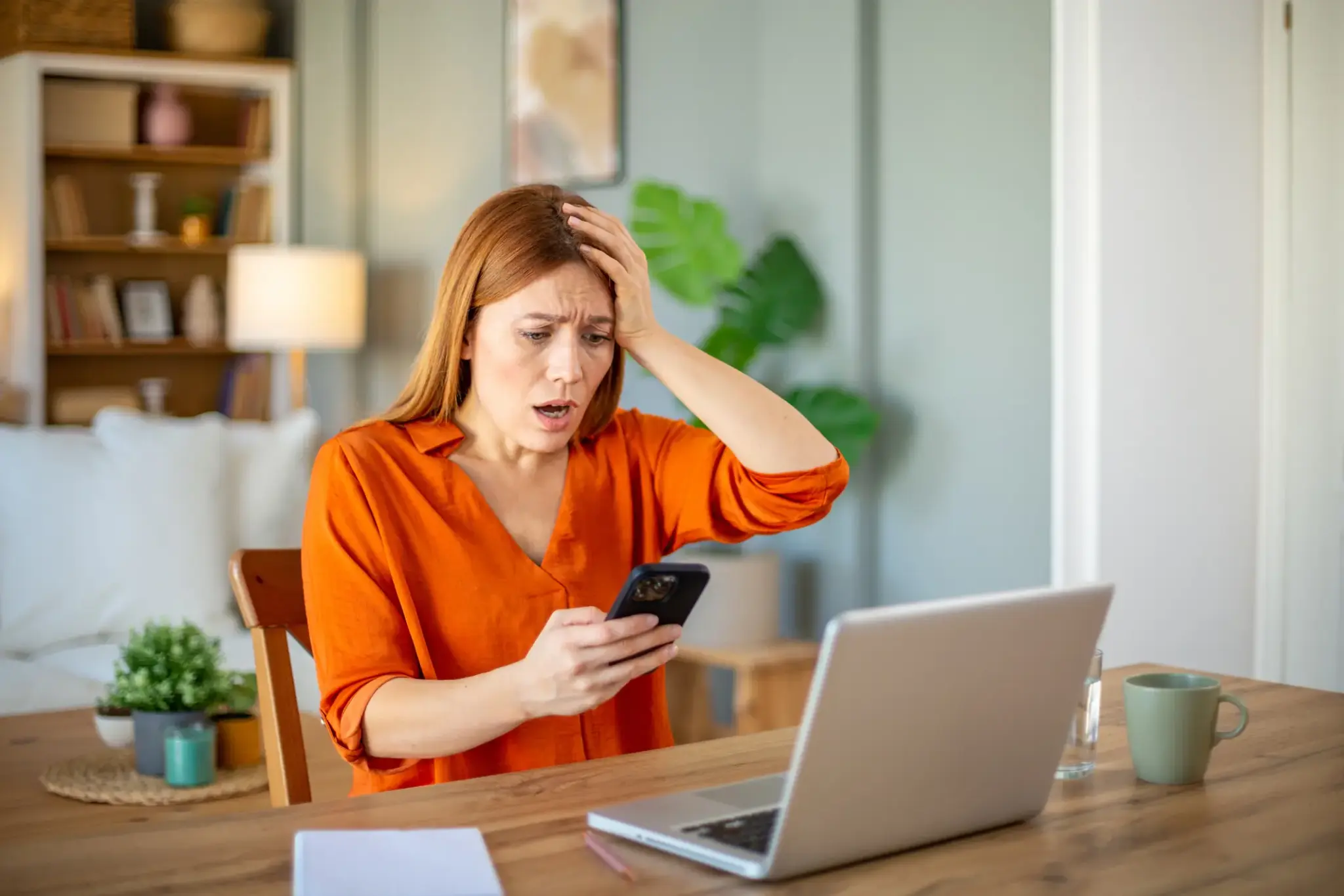 Frau schaut schockiert auf Smartphone – mögliche Phishing-Mail im privaten Umfeld