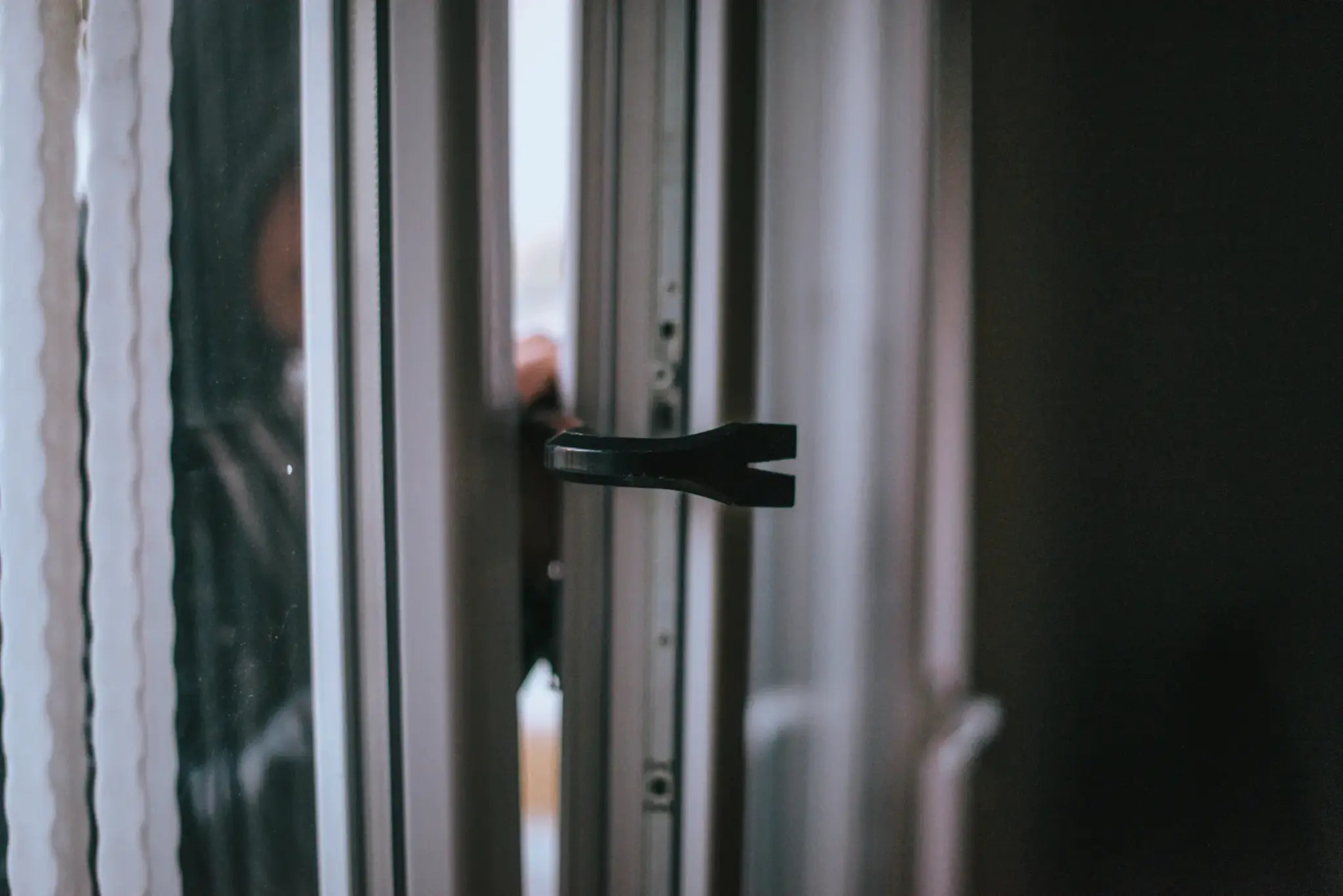 Einbrecher hebelt mit Brecheisen eine Terrassentür an einem Wohnhaus auf