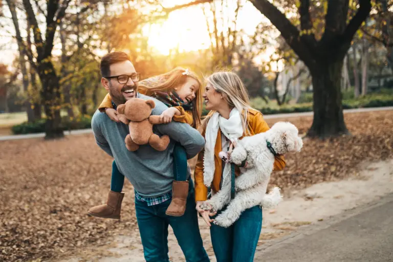 Eine fröhliche Familie mit Kind und Hund beim Spaziergang im Park – Symbol für Sicherheit, Zusammenhalt und familiären Schutz