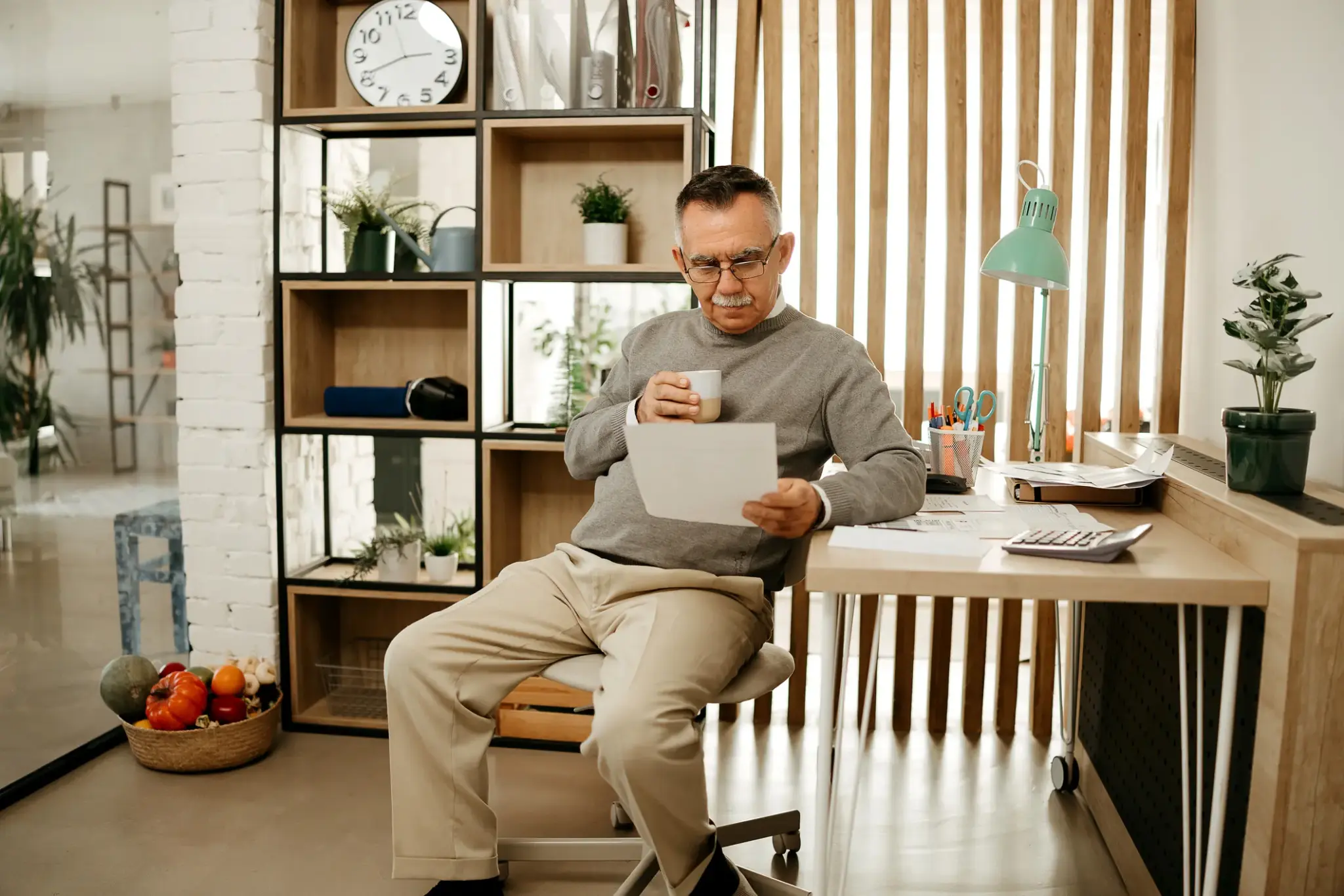 Älterer Mann liest Unterlagen im Homeoffice – Fokus auf private Altersvorsorge und Pensionskassenlösungen.