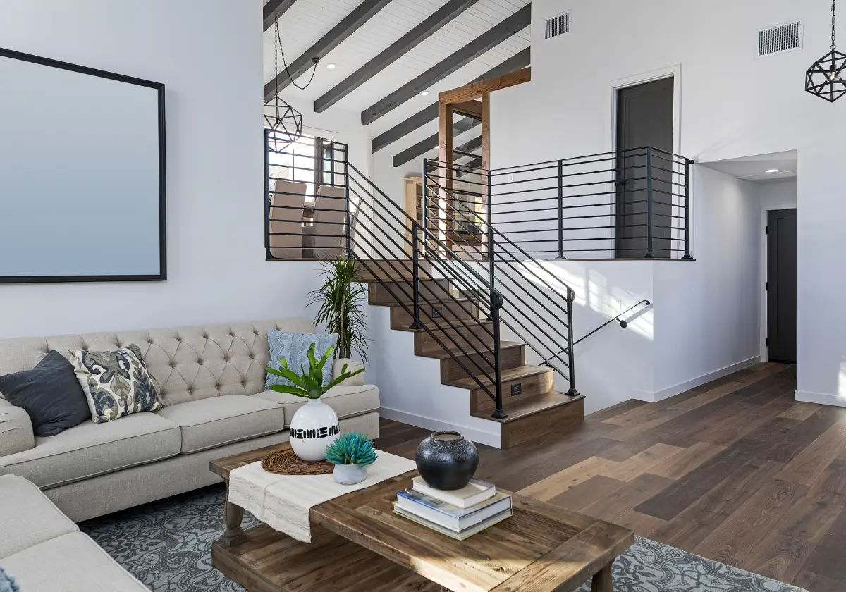 Helles Wohnzimmer mit Treppenaufgang, Sofaecke und stilvollen Holzböden