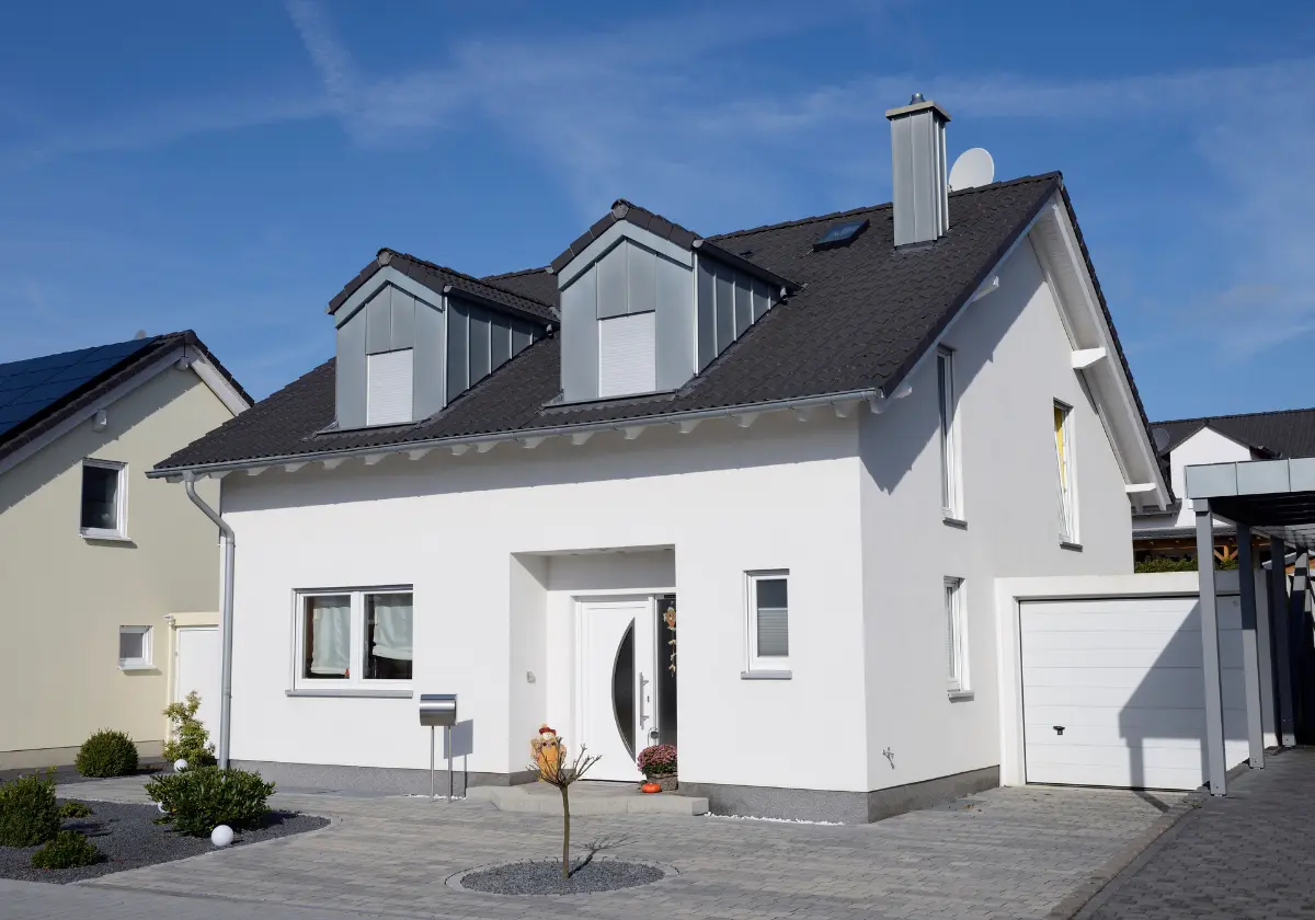 Freistehendes weißes Haus mit Garage in ruhiger Straße bei Tageslicht fotografiert