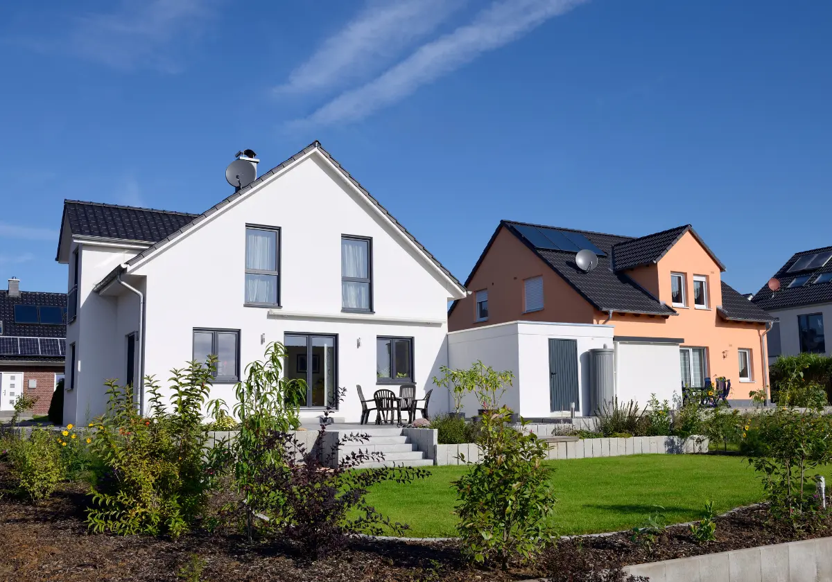 Weißes Neubau-Einfamilienhaus mit Garten und großen Fenstern in sonniger Lage