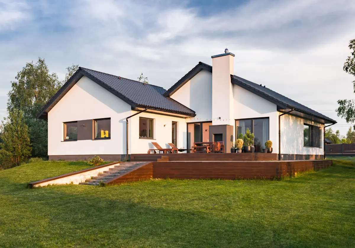 Weißes Einfamilienhaus mit Flachdach und Kamin auf grüner Rasenfläche