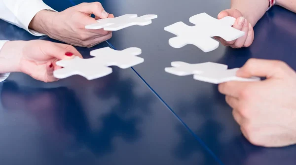 Vier Hände halten passende Puzzlestücke – symbolisch für individuelle und abgestimmte Vertragsgestaltung bei der Berufsunfähigkeitsversicherung