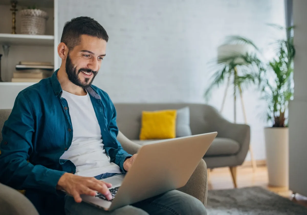 Mann sitzt entspannt auf dem Sofa und arbeitet mit einem Laptop – Symbolbild für digitale Altersvorsorge mit der Basisrente.