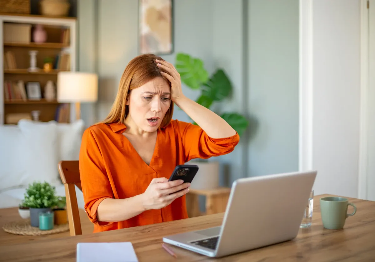 Frau schaut schockiert auf Smartphone – mögliche Phishing-Mail im privaten Umfeld