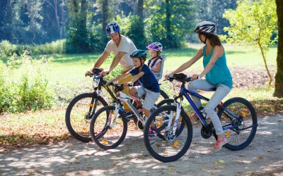 Familie mit zwei Kindern fährt gemeinsam Fahrrad im Wald – Familienzeit mit Schutzhelm und Bewegung an der frischen Luft