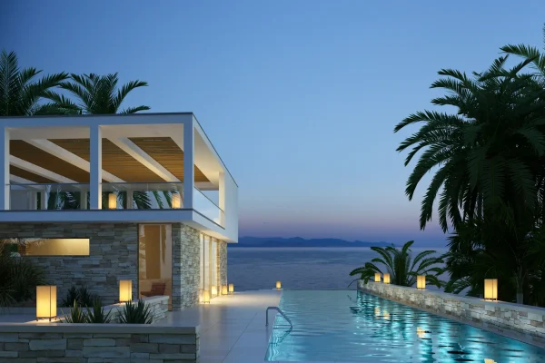 Modernes Ferienhaus mit Pool und Meerblick bei Sonnenuntergang, umgeben von Palmen und stimmungsvoller Beleuchtung