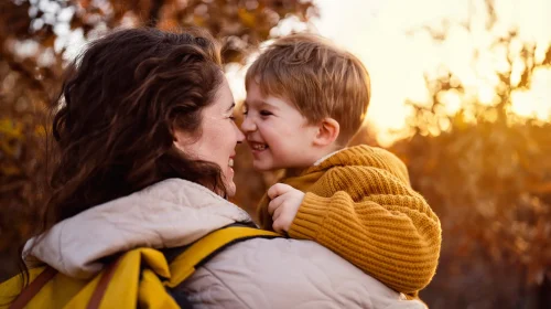 Mutter und Kind lachen sich innig an beim Spaziergang im Herbst – Geborgenheit, Lebensfreude und familiäre Nähe im Alltag.