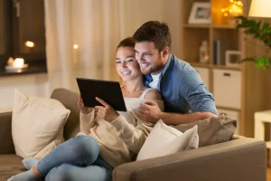 Paar sitzt gemeinsam auf dem Sofa und nutzt ein Tablet