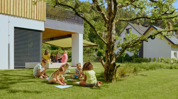 Kinder spielen im Garten eines Einfamilienhauses – Symbolbild für Sicherheit durch eine Hausversicherung.