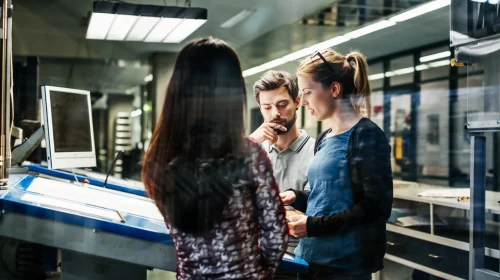 Drei Ingenieure bei der Planung und Analyse technischer Zeichnungen in einem modernen Büro