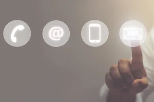 Kontaktaufnahme per Telefon, E-Mail oder Smartphone – Finger tippt auf leuchtendes Symbol für digitale Kommunikation