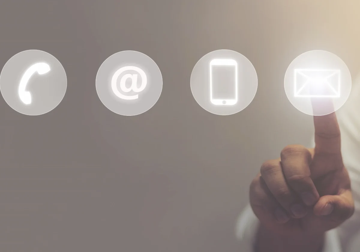 Kontaktaufnahme per Telefon, E-Mail oder Smartphone – Finger tippt auf leuchtendes Symbol für digitale Kommunikation