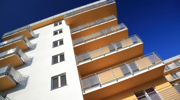 Modernes Mehrfamilienhaus mit Balkonen und blauem Himmel