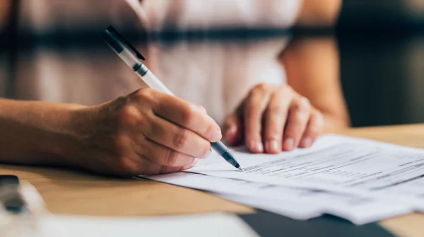 Nahaufnahme einer Hand, die ein Formular ausfüllt – Symbolbild für vertragliche Absicherung durch eine Privatrechtsschutzversicherung
