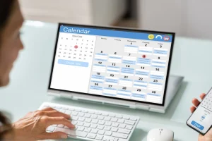Frau vereinbart online einen Termin über Kalender-App auf Laptop und Smartphone – digitale Terminbuchung leicht gemacht