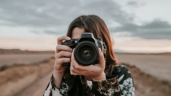 Fotografin mit Kamera im Fokus – symbolisiert kreative Berufe mit hohem Bewegungs- und Verletzungsrisiko