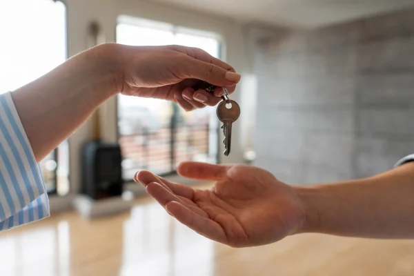 Eine Hand übergibt einen Wohnungsschlüssel an eine andere – symbolisch für Mietverhältnisse und rechtliche Absicherung für Vermieter