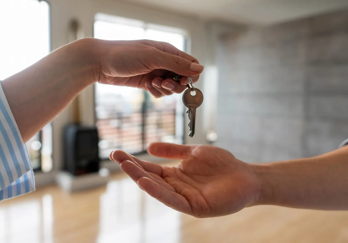 Eine Hand übergibt einen Wohnungsschlüssel an eine andere – symbolisch für Mietverhältnisse und rechtliche Absicherung für Vermieter