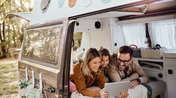 Familie im Wohnmobil beim gemeinsamen Tablet-Schauen, Camping in der Natur