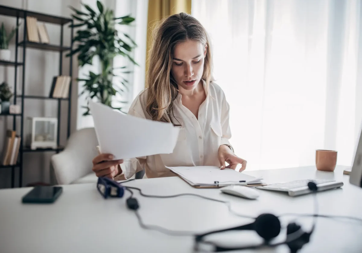 Junge Frau am Schreibtisch prüft aufmerksam Unterlagen – sinnbildlich für den sorgfältigen Vergleich bei der BU-Versicherung.