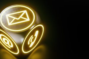 Leuchtender Würfel mit Symbolen für E-Mail, Telefon und Internet auf dunklem Hintergrund