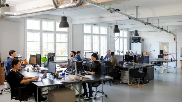 Büromitarbeitende an modernen Arbeitsplätzen – Symbolbild für betriebliche Unfallversicherung und Arbeitssicherheit im Unternehmen