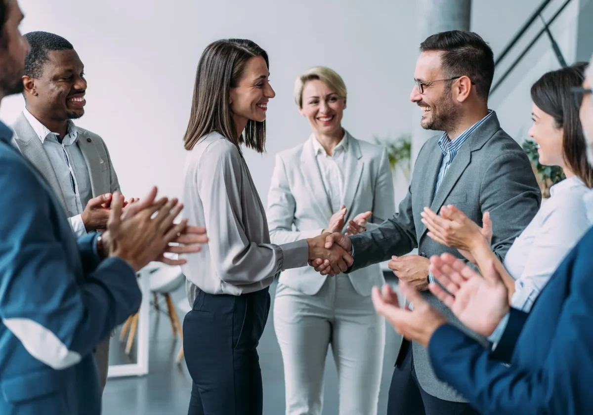 Geschäftsleute gratulieren einer Kollegin bei der Arbeit – symbolisch für betriebliche Arbeitskraftabsicherung im Team