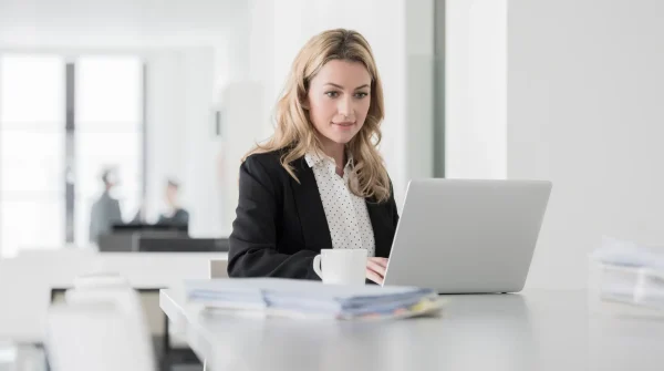 Geschäftsfrau im Büro arbeitet konzentriert am Laptop und informiert sich online zur Betriebshaftpflichtversicherung