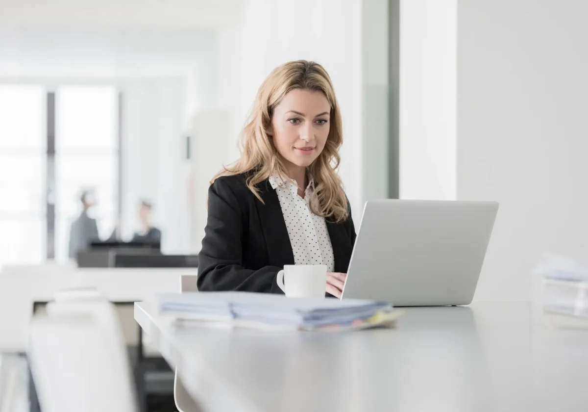 Geschäftsfrau im Büro arbeitet konzentriert am Laptop und informiert sich online zur Betriebshaftpflichtversicherung