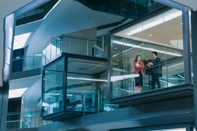 Zwei Personen im Gespräch hinter großflächiger Glasfassade in einem modernen Bürogebäude – Symbolbild für gewerbliche Glasversicherung