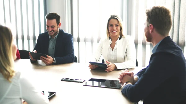 Vier Personen im Business-Outfit sprechen in einem Besprechungsraum über eine gewerbliche Sachversicherung